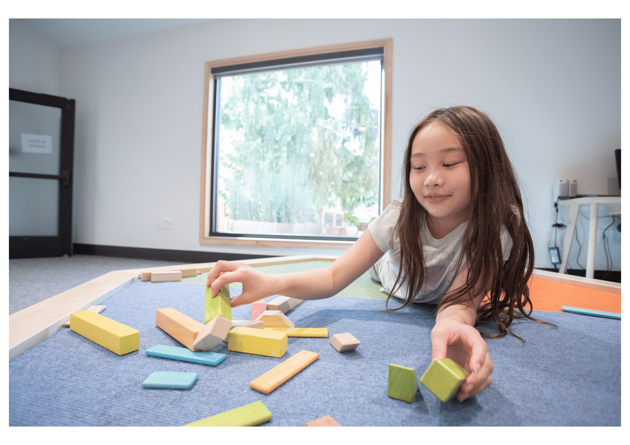 Child lays on the ground and builds with blocks
