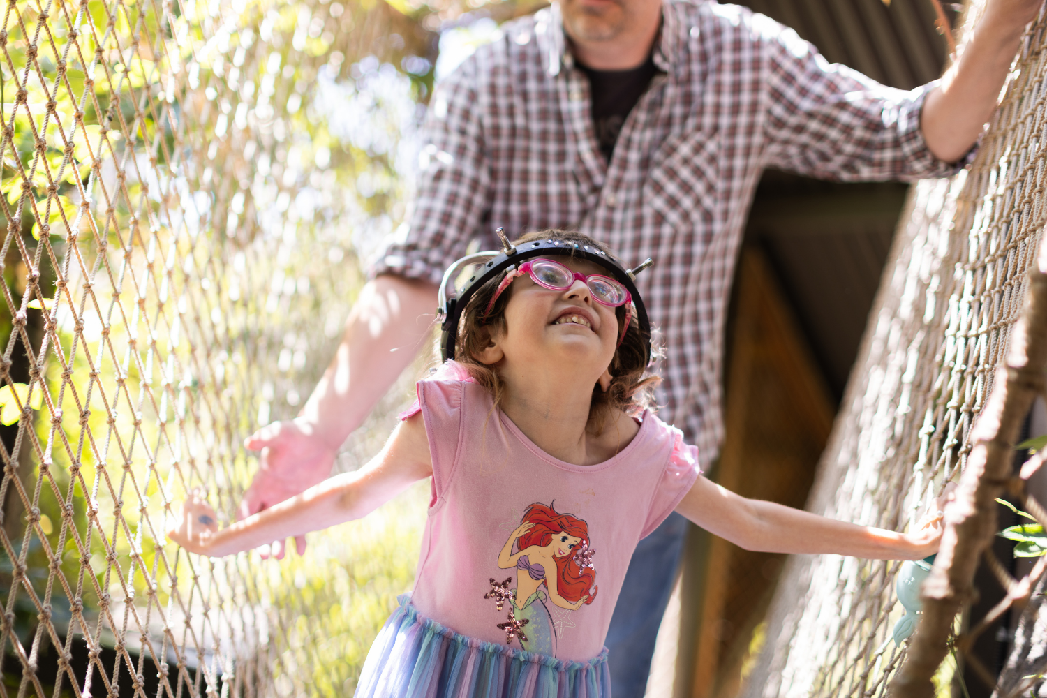 Girl walking on treehouse with father following behind her