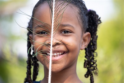 Girl holds a peacock feather in front of her face